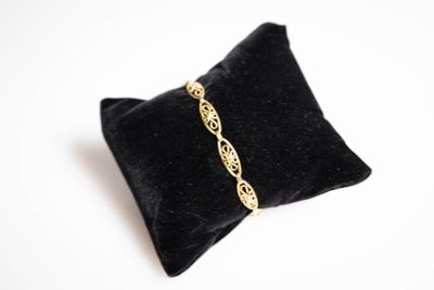 un gros plan sur un oreiller noir sur lequel repose un bracelet doré