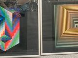 two different colored paintings in a glass case on the wall
