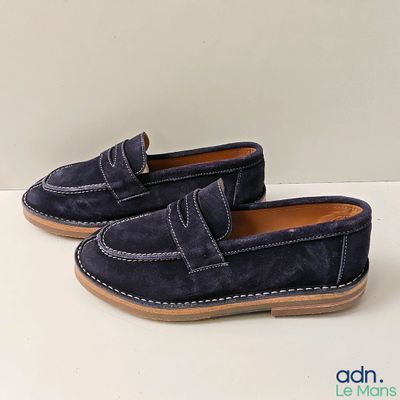 une paire de mocassins en daim bleu pour homme posés sur un fond blanc