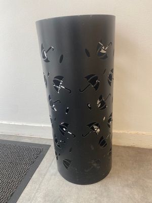 un vase noir posé par terre près d'un mur