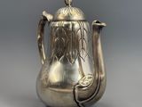 une théière ancienne en argent ornée d'un oiseau sur l'anse