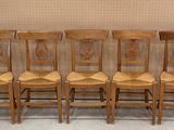 Quatre chaises en bois sont alignées en rang contre un mur