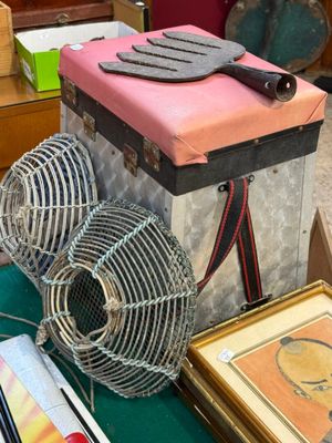 une valise rose posée sur une table à côté d'un ventilateur