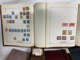 an open book with stamps on it sitting on a table next to a stack of books