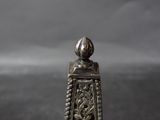 an old silver object on a black surface with a gray background