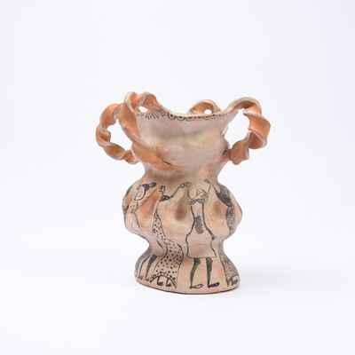 un petit vase avec un motif sur une surface blanche