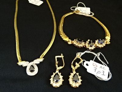 trois bijoux posés sur un tissu noir, accompagnés d'une étiquette de prix