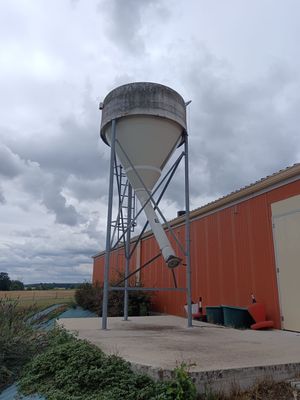 un château d'eau situé à côté d'un bâtiment, au bord de la route