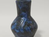 un vase bleu et noir posé sur une surface blanche