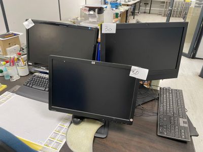 two computer monitors sitting on a desk next to each other