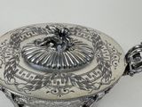 a silver plate with a lid that has a design on it
