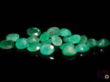 a close up of a pile of green stones on a black surface