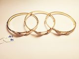 trois bracelets rigides en or sertis de diamants, sur fond blanc