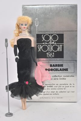 une poupée Barbie en robe noire, avec un sac à main rose et un micro