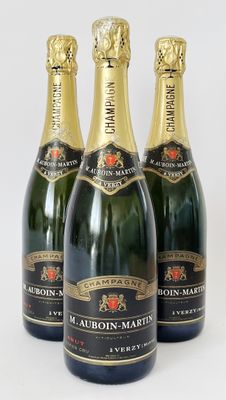 quatre bouteilles de champagne sont alignées sur une surface blanche