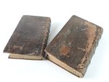 two old books sitting on top of each other on a white surface