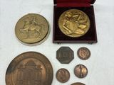 un assortiment de pièces comprenant une médaille en or, une pièce en argent et une boîte rouge