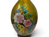 un vase orné de fleurs peintes, posé sur une surface blanche
