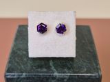 une paire de boucles d'oreilles « cubicge » violettes posées sur un bloc de marbre