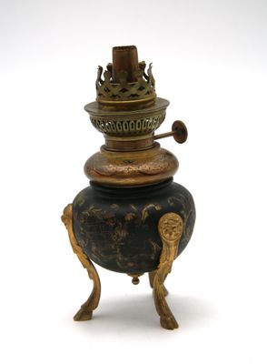 un vase noir et doré posé sur un socle, sur fond blanc