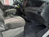the interior of a white truck with the door open and the driver ' s seat down