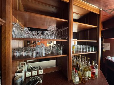 many glasses and bottles on the shelves in the bar
