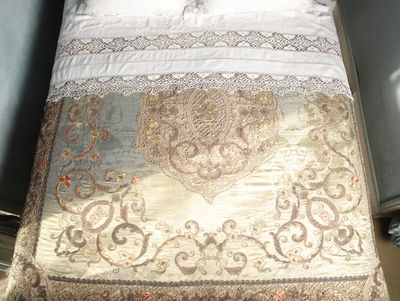 a bed with a white and gold comforter on it