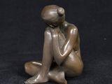 statue of a woman sitting on the ground with her hands on her knees