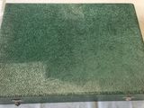 an old green suitcase sitting on top of a white sheet