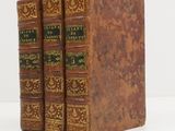 two old books sitting on top of each other on a white surface