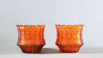 deux vases en verre orange posés sur une surface blanche