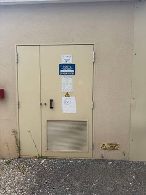 une borne d'incendie devant un immeuble, sur laquelle est apposé un panneau