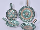 trois pièces de poterie vertes et marron posées sur une surface blanche