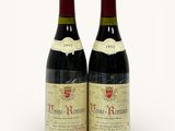 two bottles of red wine sitting next to each other on a white surface