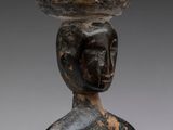 un gros plan sur la statue d'une femme portant un bol sur la tête