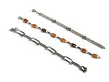 trois bracelets en verre argenté et orange posés sur une surface blanche