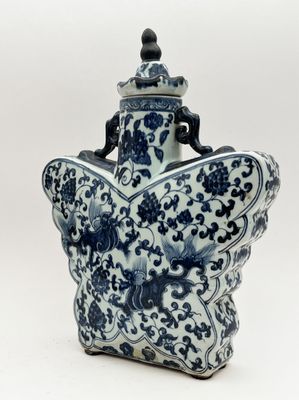 vase bleu et blanc orné d'un papillon sur le col