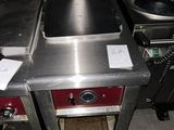 une cuisinière sur laquelle est posée une marmite dans une cuisine