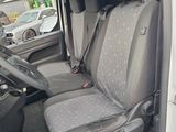the interior of a white van with grey seat covers and a black steering wheel