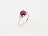 a close up of a ring with a ruby stone and diamonds