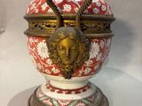 a red and white vase with a gold face on it