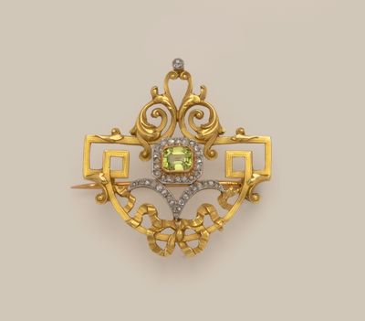 a gold and diamond broochle with a green stone in the center