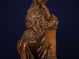une statue en bronze représentant une femme assise sur une table
