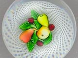 un saladier en verre rempli de fruits et de légumes posé sur une table