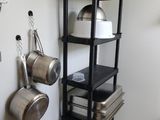 une étagère avec des casseroles et des poêles dans une cuisine