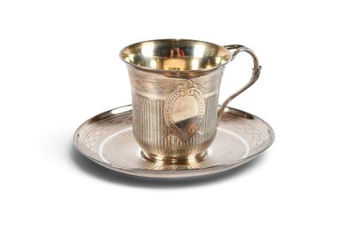 une tasse et une soucoupe anciennes en argent, posées sur une soucoupe, sur un fond blanc