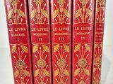 five red books with gold designs on them sitting on a white surface