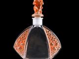 an orange glass perfume bottle with a black background
