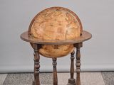 un vieux globe en bois posé sur un socle, au milieu d'un sol à damier