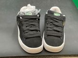 black puma sued sneakers with white soles on a black surface